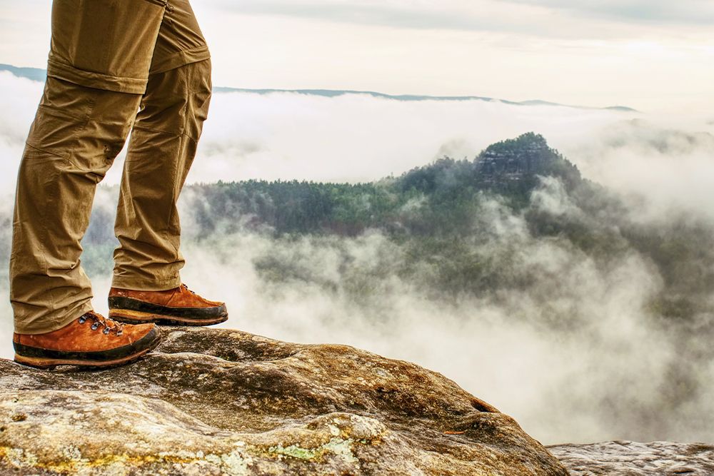 Man hiker legs with windproof trousers and hiking boots